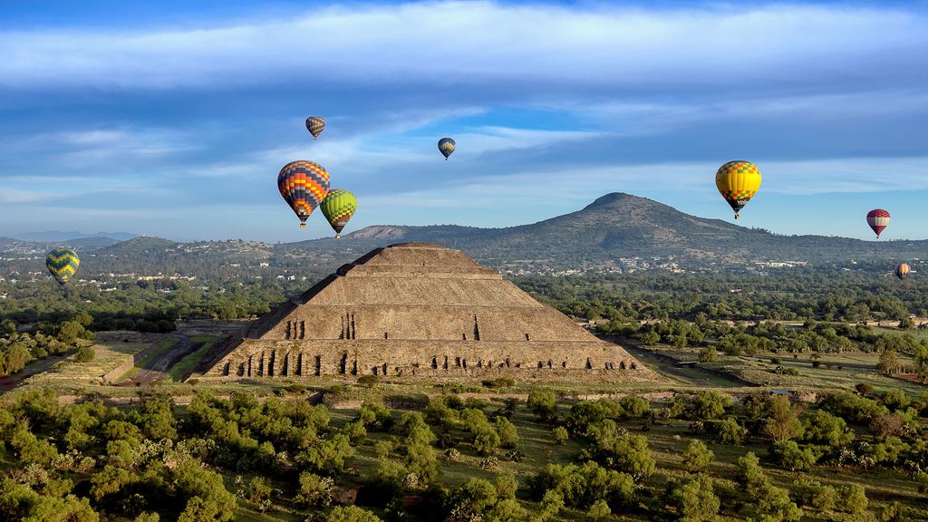 Hot air balloons flying above a pyramid in the Teotihuacan archaeological zone, seen from above