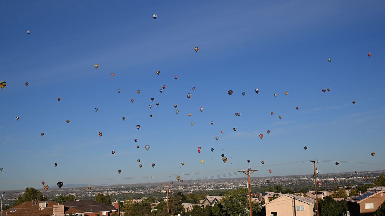 Dozens of hot air balloons drifting low over houses in Albuquerque during the International Balloon Fiesta