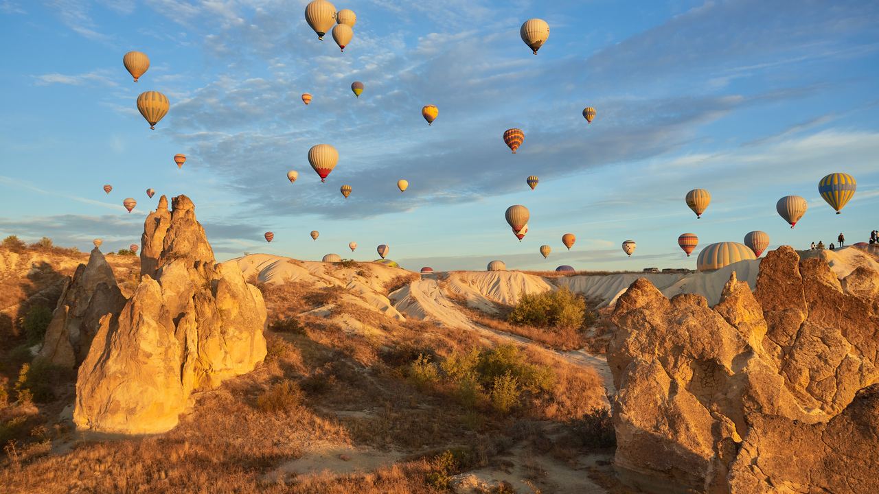 Dozens of hot air balloons in flight at sunrise above the fairy chimneys of Göreme, Cappadocia
