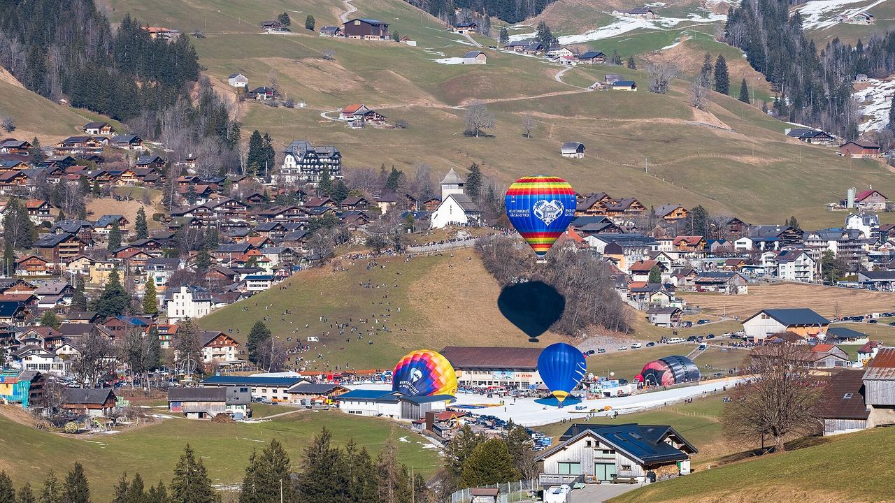 Hot air balloons being inflated on the snow-covered field at the Festival International de Ballons in Chateau-d'Oex, Switzerland