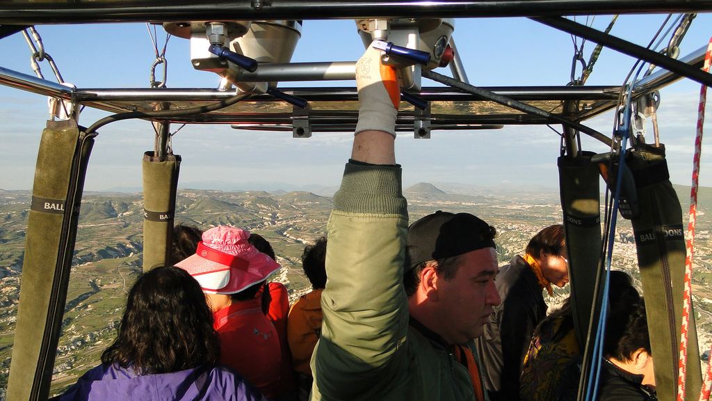 Passengers of different ages standing close together in a hot air balloon basket in flight over Goreme, Cappadocia