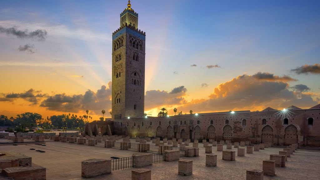 The minaret of the Koutoubia mosque in Marrakech catching the first sunlight, with the low city around it